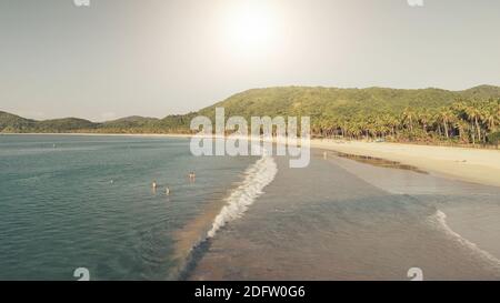 Sun over sand beach at sea coast aerial. Summer tropic paradise vacation at ocean bay. Nature landscape and seascape of El Nido Island, Philippines, Asia. Cinematic people relax at sunny day Stock Photo