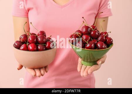 Woman with bowls of tasty cherry on color background Stock Photo