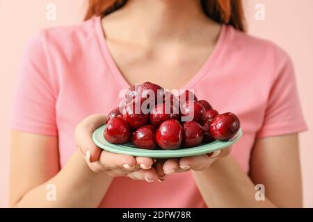 Woman with bowl of tasty cherry on color background Stock Photo