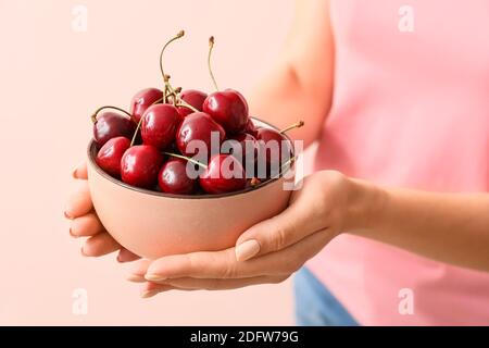 Woman with bowl of tasty cherry on color background Stock Photo