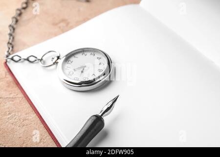 Notebook, pocket clock and nib pen on table Stock Photo