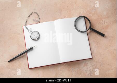 Notebook, pocket clock, magnifier and nib pen on table Stock Photo