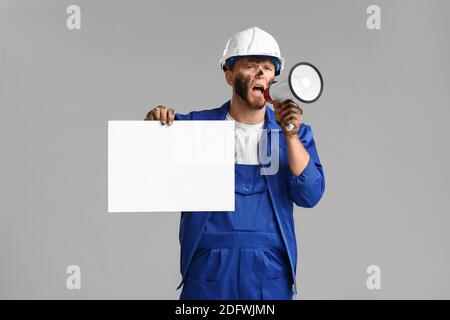 Protesting miner man with placard and megaphone on grey background Stock Photo