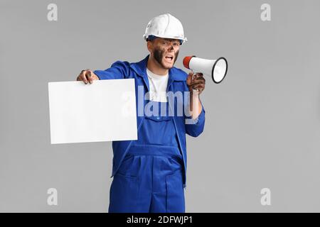 Protesting miner man with placard and megaphone on grey background Stock Photo