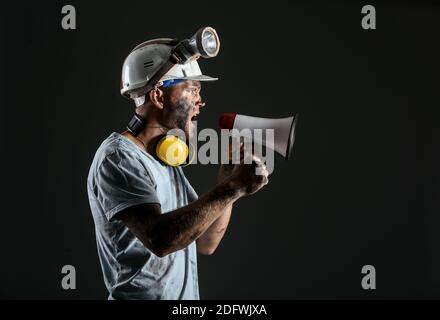 Protesting miner man with megaphone on dark background Stock Photo