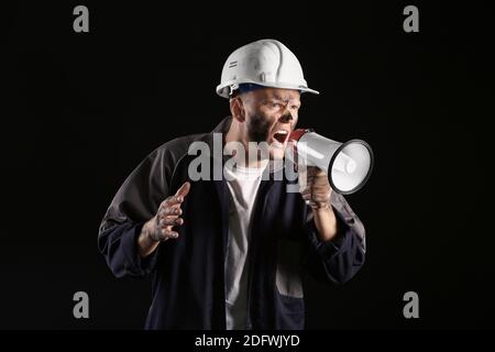 Miner man with megaphone on dark background Stock Photo