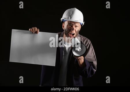 Miner man with megaphone and placard on dark background Stock Photo