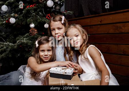 Beautiful happy laughing children in New Year interior with Christmas tree. The concept of a family holiday. Christmas Happy funny children sisters hu Stock Photo