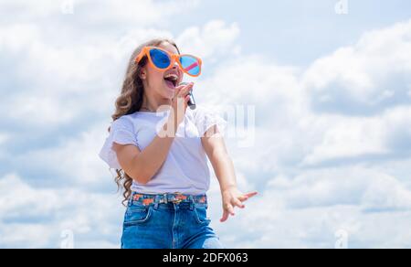 teen girl singing song in microphone on sky background, music party. Stock Photo