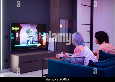 Photo of young couple playing video games at home at night Stock Photo