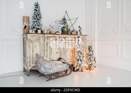 Christmas decoration on ancient vintage old commode chest of drawers. Hand made craft gifts, candels and a tree at background. Stock Photo