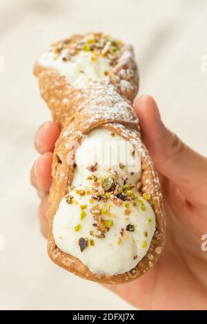 Close up of a fresh Sicilian Cannoli, held by hand. . Stock Photo