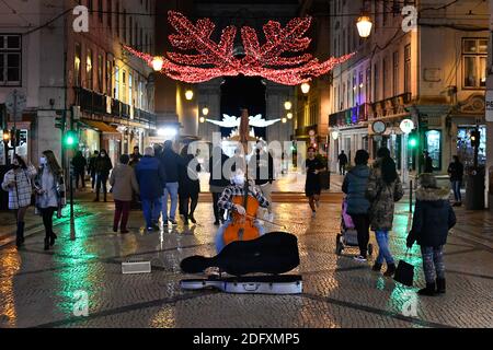 Lisbon, Portugal. 03rd Dec, 2020. A musician wearing a face mask plays a cello in the middle of Rua de Augusta in the district of Baixa.Portugal implemented an emergency regulation that forbids the movement of people between the different districts and municipalities of the country during the celebrations of Christmas and the New Year. Credit: SOPA Images Limited/Alamy Live News Stock Photo