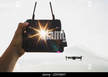 Close up drone remote control in hand. Wireless drone control. Silhouette and sun at sunrise. Stock Photo