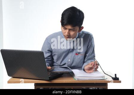 portraits of Asian men seriously working on reports on computers and notebooks. office employee bustling concept with isolated white background Stock Photo