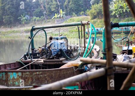 Old dredger bounded beside the bamboo bridge on a small river in Bangladesh Stock Photo