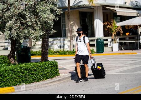 Airbnb tourists walking in Miami Beach with luggage suit cases Stock Photo