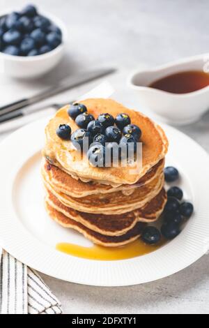 Homemade pancakes with blueberries and maple syrup on white plate. Sweet breakfast food. Toned image Stock Photo