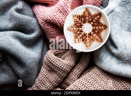 Coffee with a snowflake pattern on a warm knitted sweaters  background. Top view Stock Photo