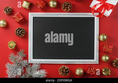 Photo frame with free black space around Christmas decorations and gifts on a red background. Top view, free space for text Stock Photo