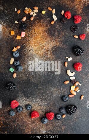 Frame made of mixed dried and raw ripe berry and fruit with nuts, top view with copy space, on old dark table Stock Photo
