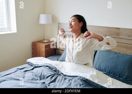 Young woman stretching in bed Stock Photo