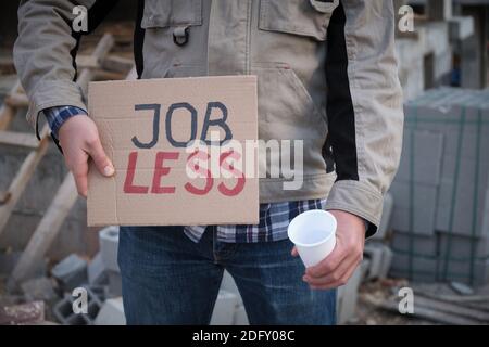 Construction worker stands with placard Jobless opposite construction site Stock Photo