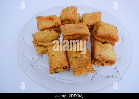 Indian tea time snack Khaari biscuit. Namkeen salty Masala khari served in white plate. Close up white background. Indian munching item. Stock Photo