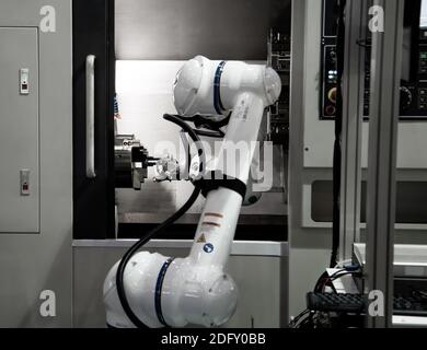 Automated process industrial robot loading metal part to CNC machine. Industrial manufacturing Stock Photo