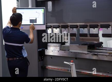 Industrial technician opearting CNC synchronize hydraulic press brake. Metalworking manufacturing factory Stock Photo