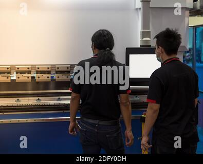 Industrial technician opearting CNC synchronize hydraulic press brake. Metalworking manufacturing factory Stock Photo