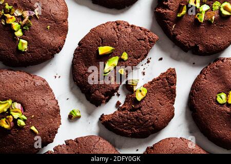 Homemade vegan chocolate chip cookies with pistachios on a white marble background. Vegan baking concept. Stock Photo
