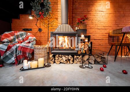 Fireplace area of a beautiful loft-style interior with real brick and concrete floors decorated for the New Year holidays. The concept of home comfort Stock Photo