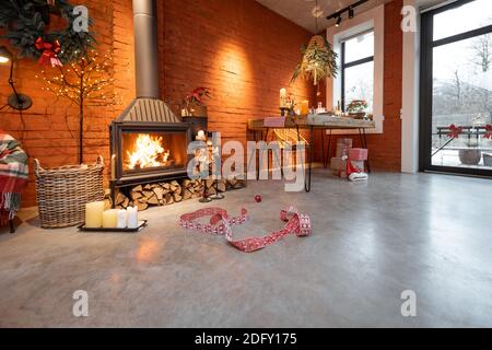 Fireplace area of a beautiful loft-style interior with real brick and concrete floors decorated for the New Year holidays. The concept of home comfort Stock Photo