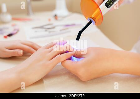 Medicine, manicure and prosthetic nail. In the nail salon, a procedure for prosthetics of the nail on the hand is carried out. In the hands of master Stock Photo