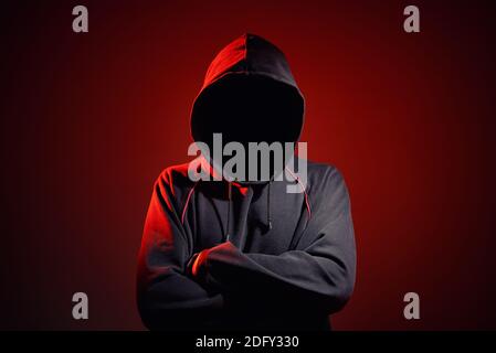 Silhouette af man without face in hood on a red background. Anonymous crime concept Stock Photo