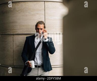Young businessman with coffee in hand making call Stock Photo