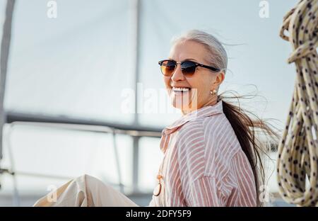 Laughing mature woman wearing sunglasses and looking at camera Stock Photo