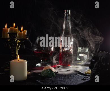 A bottle of red liquid like blood and a glass. Magical potion. The concept of wizards, witchcraft and magic. Halloween. Stock Photo