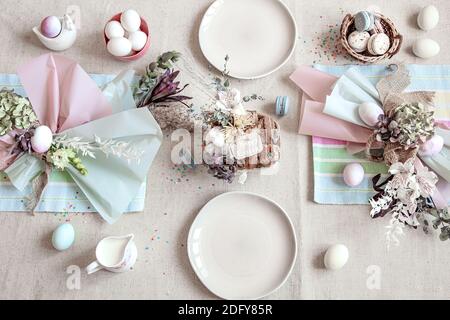 Decorated holiday table with white plates, eggs and floral arrangement. Happy easter concept. Stock Photo