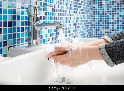 Child washing hands with antibacterial soap and water performing basic protective measures against spreading of coronavirus COVID-19 disease Stock Photo