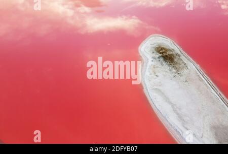 The island is covered with salt on a pink lake, top view on a background of pink water. Stock Photo
