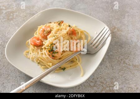 Appetizer spaghetti with shrimps, garlic and herbs, Mediterranean seafood on a small plate, rustic gray background with copy space, selected focus, na Stock Photo