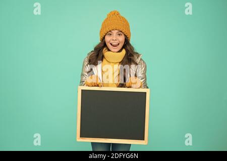 Fresh information. Schedule and working hours. Open hours. Winter entertainment and activities. Happy hours. Promotion concept. Smiling girl wear winter outfit show blank chalkboard copy space. Stock Photo