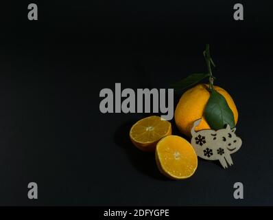 Tangerine cut with a green leaf on a black background. Goby symbol of 2020 Stock Photo