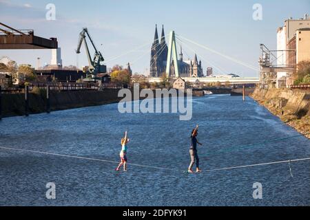 man and woman on slacklines in the Rhine harbor in the district Deutz, in the background the cathedral and Severins bridge, Cologne, Germany. Stock Photo