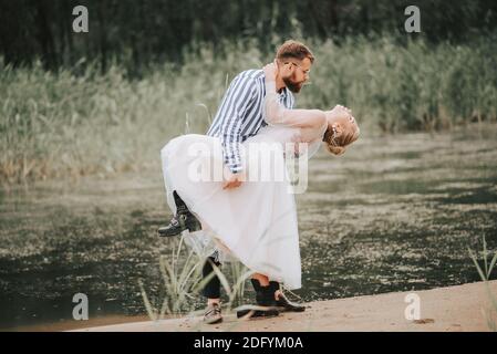 Man and woman passionately embrace on the beach line. Loving couple dancing in nature by the water. Stock Photo