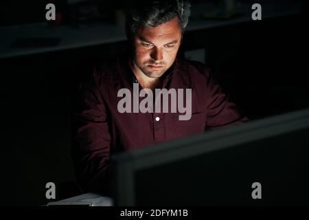 Portrait of a middle age focused businessman working late night in office - man working late for deadlines Stock Photo