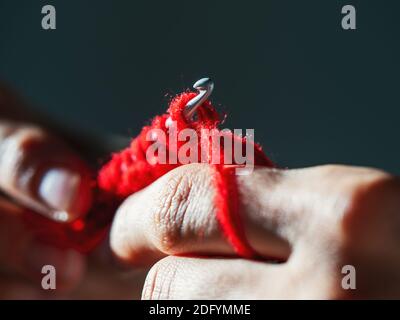 Close-up crocheting with red wool yarn on a dark background Stock Photo