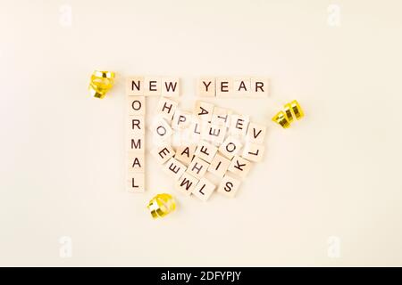 Words New Year and New Normal are laid out in wooden letters, various letters are scattered between them, from which words of support for next year ar Stock Photo